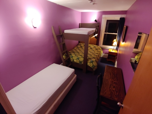 Purple Room, Three Beds, Desk & Night Table With Lamp.  One Window.