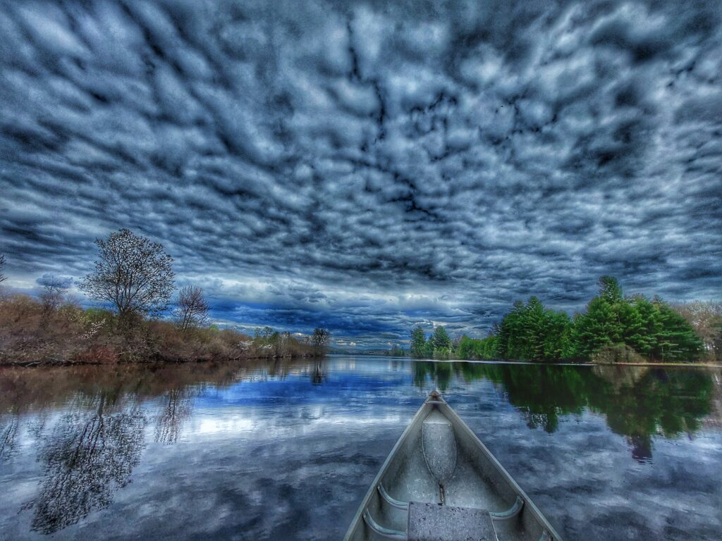 canoe on Madawaska River under cloudy skies reflected in the water