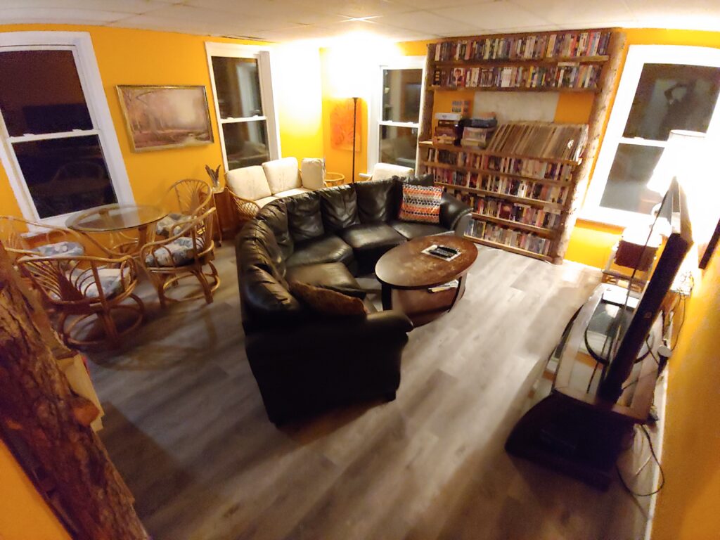 orange room with curved black couch, 65" tv, collection of VHS & DVD