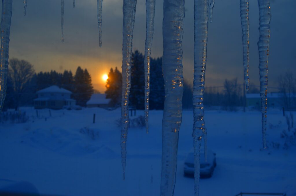 rising sun over frozen backyard of Arlington refracted in icicles