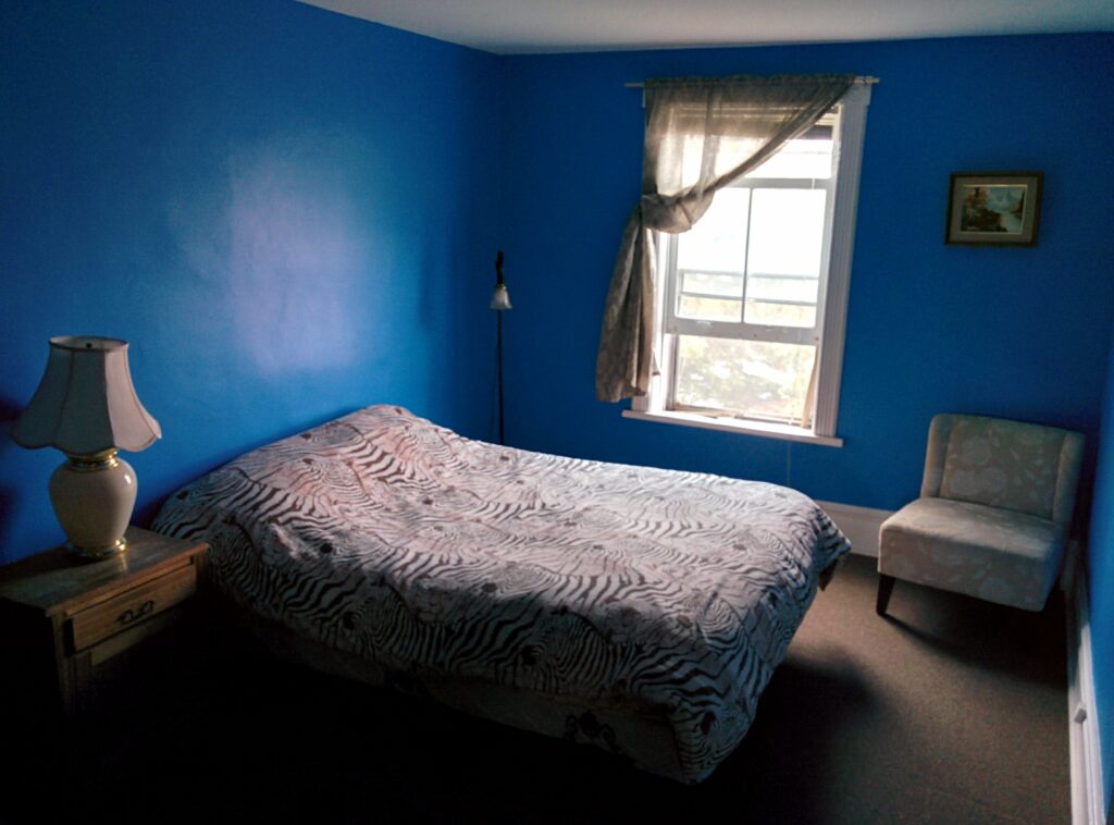 Blue room, one window, queen size bed chair, table, two lamps