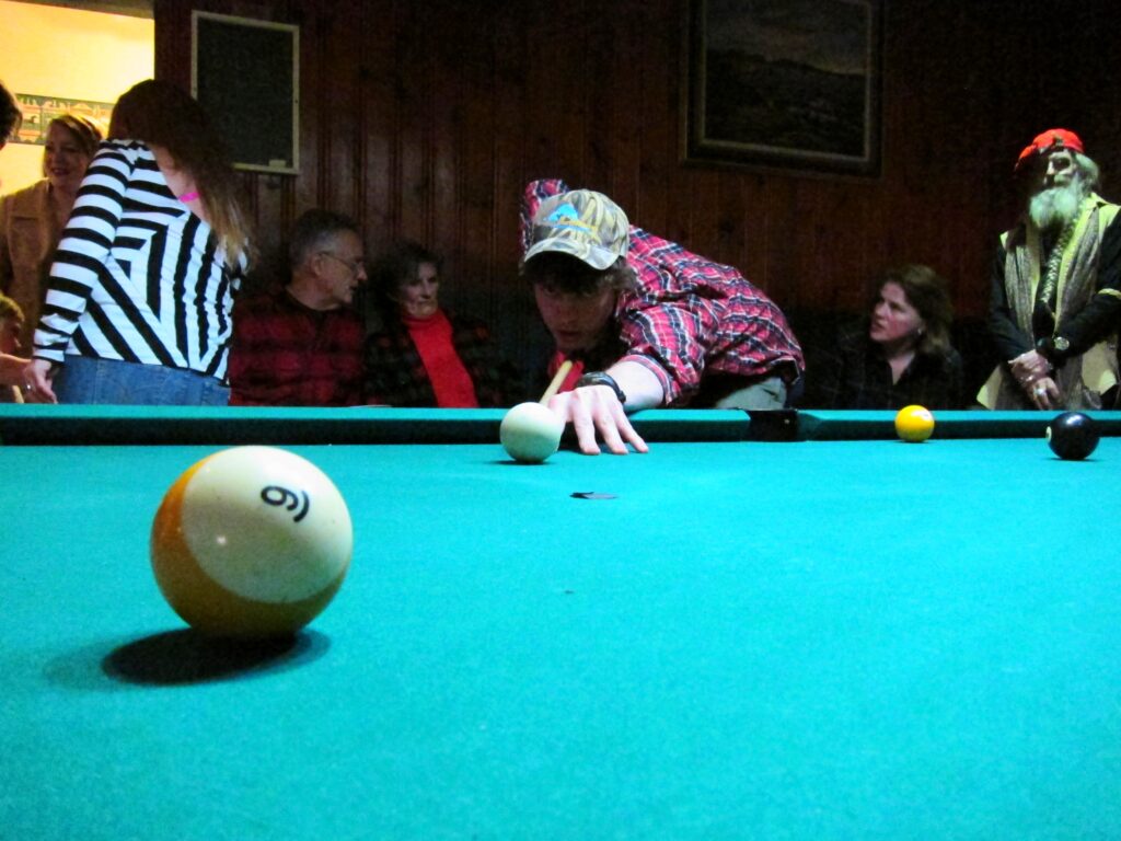 fella aiming for 9 ball with people chatting in background