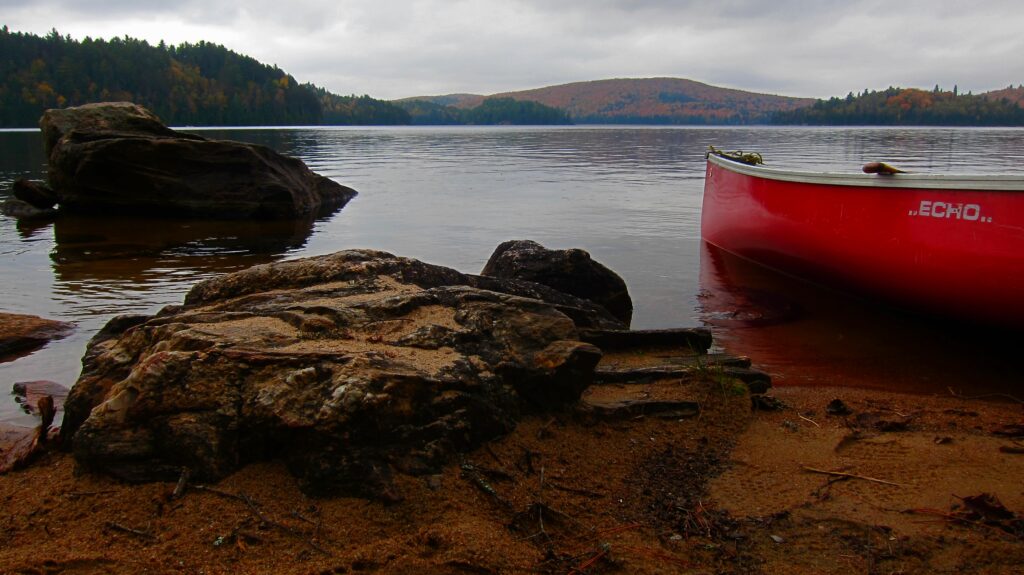 Canoe and rock on beach at Booth Lake in autumn