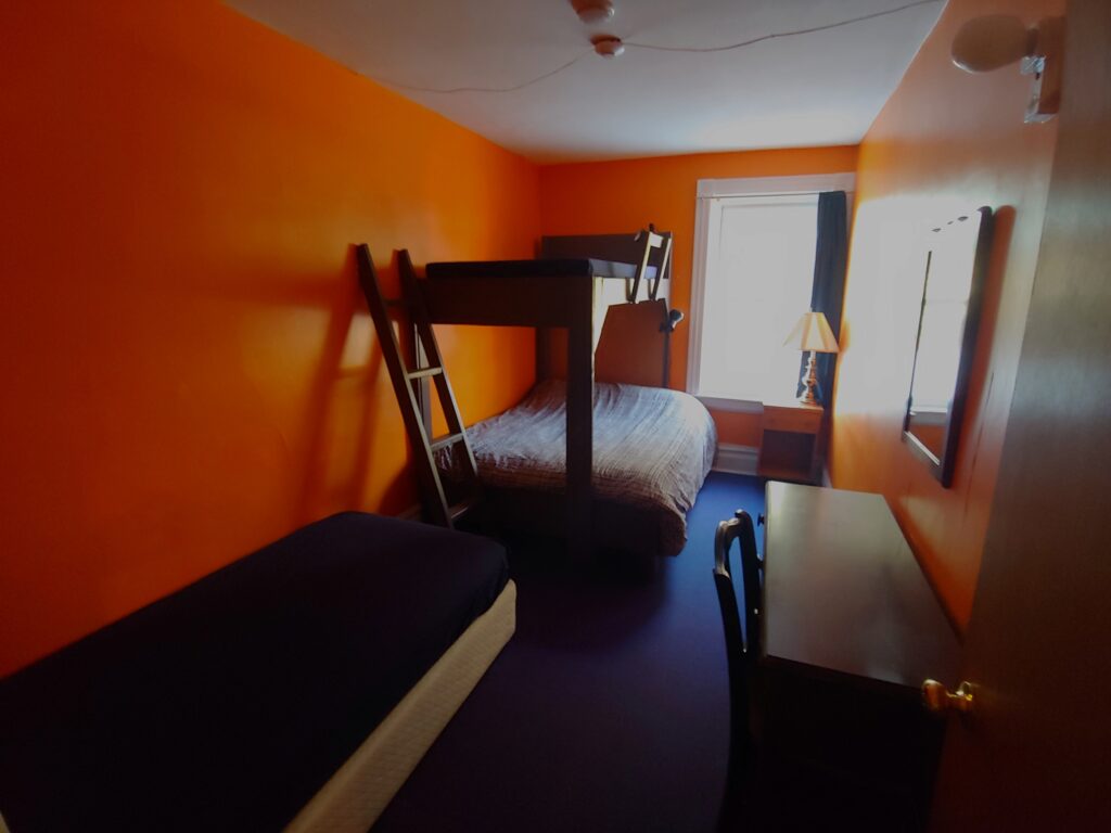 orange room with a bunk bed, single bed, desk & night table