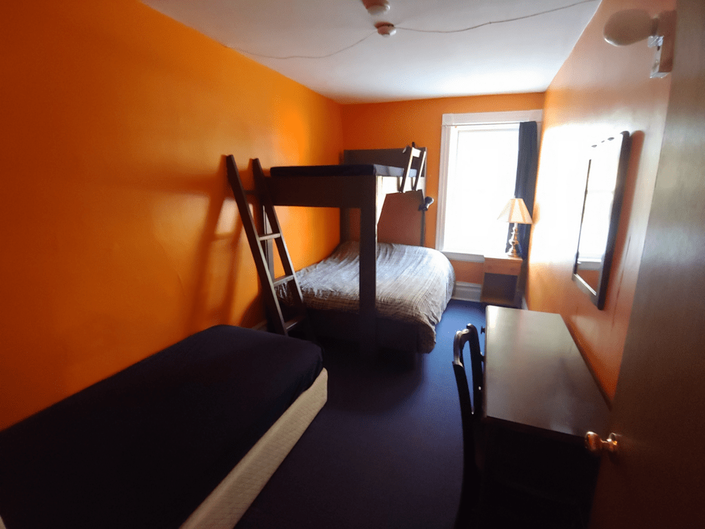 orange room, single bed, bunk bed, desk, lamp, bright window