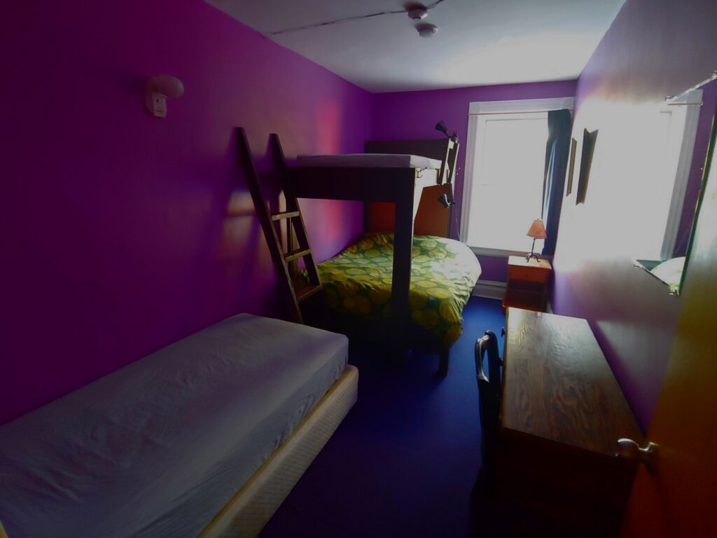 purple room with a bunk bed, single bed, desk & night table
