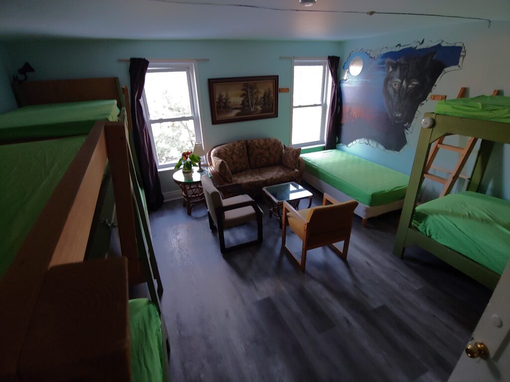 three bunk beds, one single bed, love seat, coffee table, two chairs, wolf mural