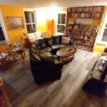 orange room with curved black couch, 65" tv, collection of VHS & DVD