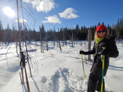 snowed over pond with woman standing holding ski poles