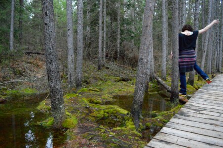 Woman walking on log in the forest beside a wooden pathway