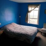 Blue room, one window, queen size bed chair, table, two lamps