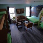 three bunk beds, one single bed, love seat, coffee table, two chairs, wolf mural